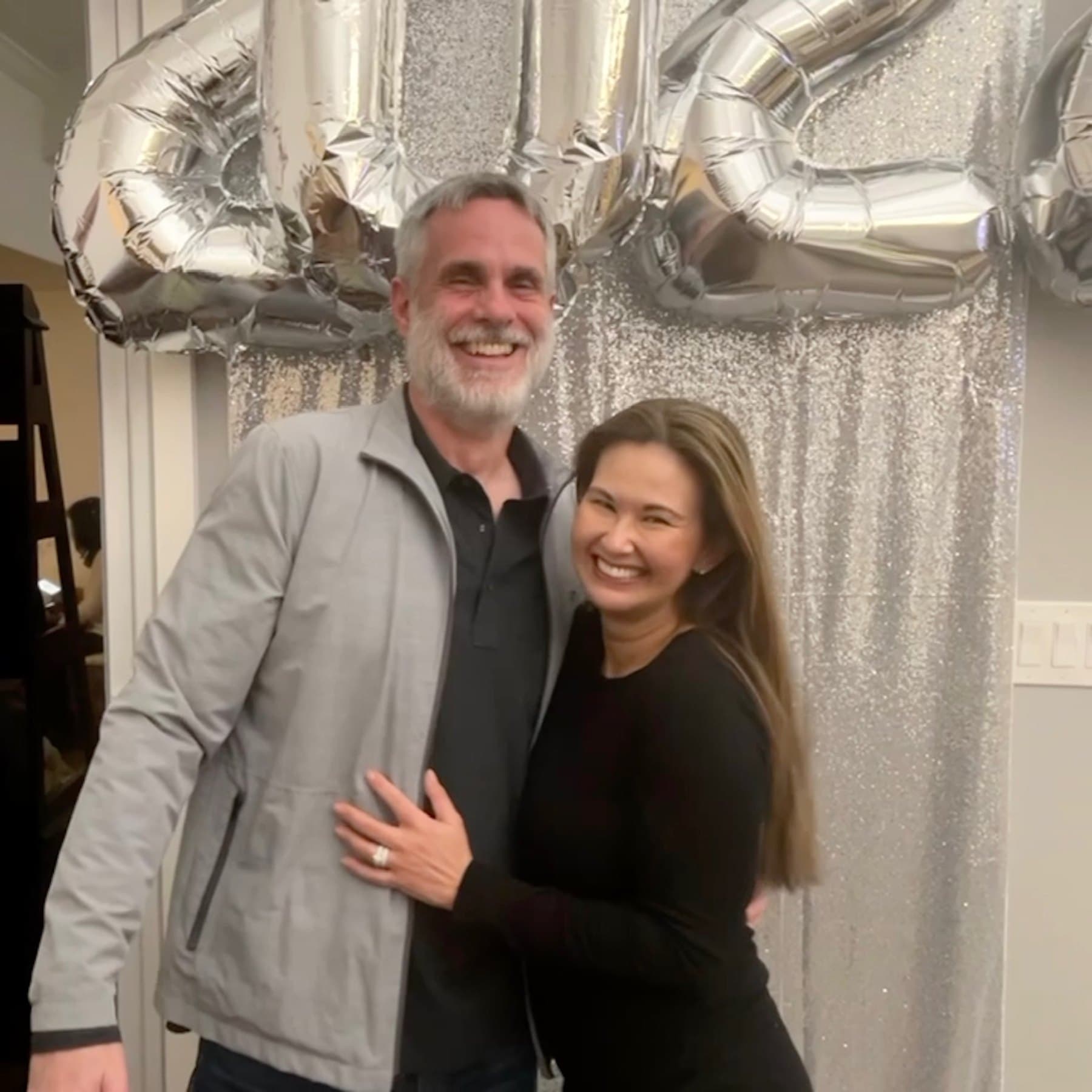 Cris and Shirley laughing together in front of birthday balloons