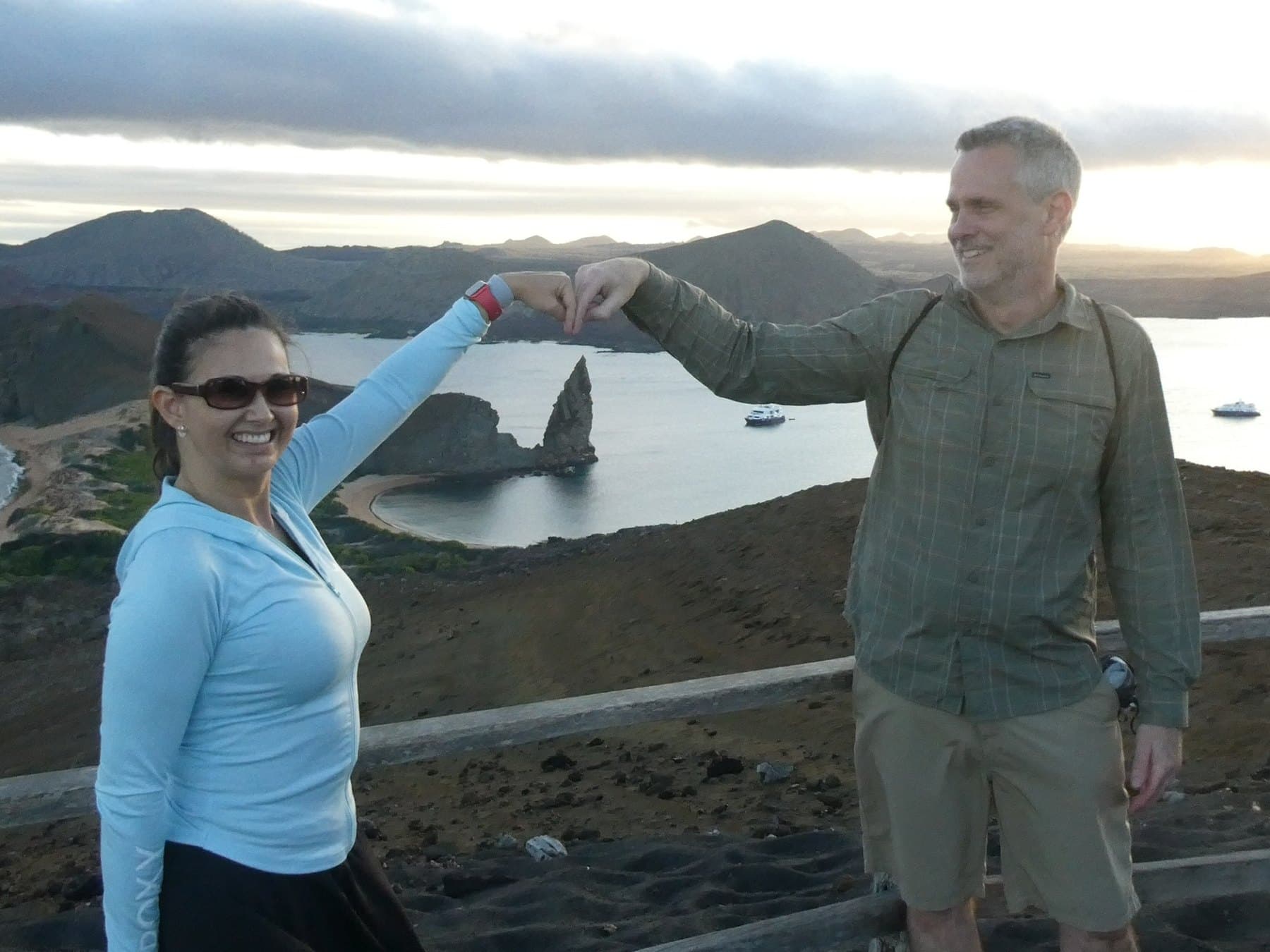 Shirley and Cris forming a heart with their hands above an island view