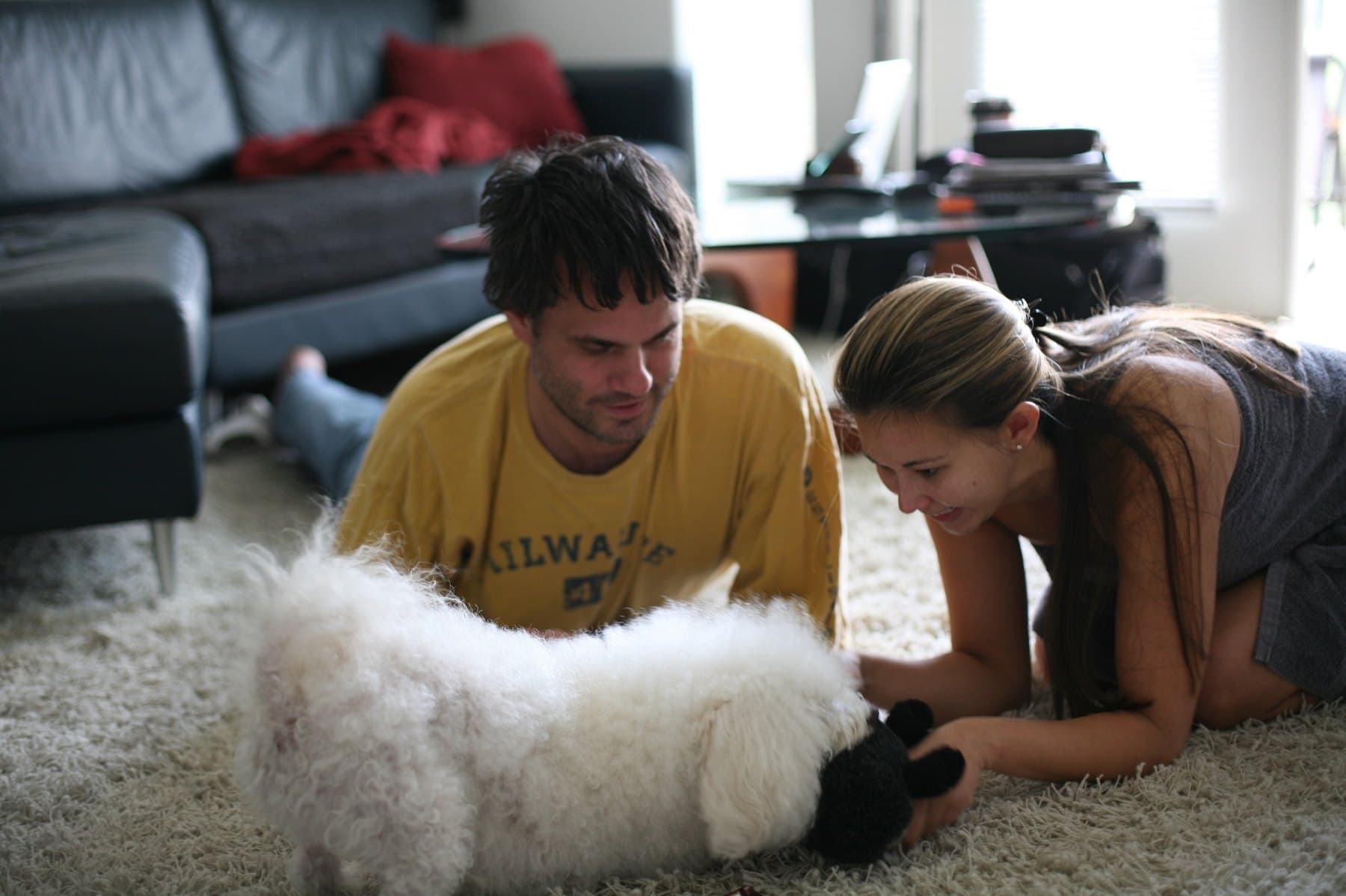 Cris and Shirley lying on the floor with one of their fluffy pups
