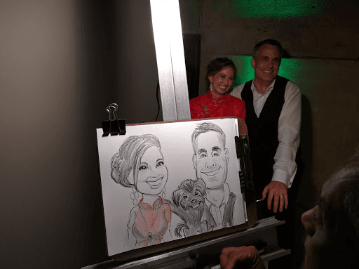 Shirley and Cris posing beside their wedding caricature